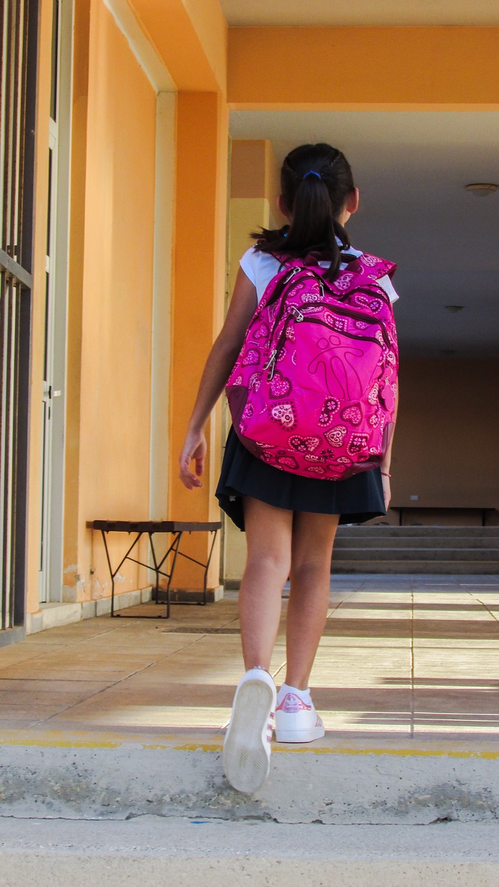 Bambina studente con zaino, vista di spalle